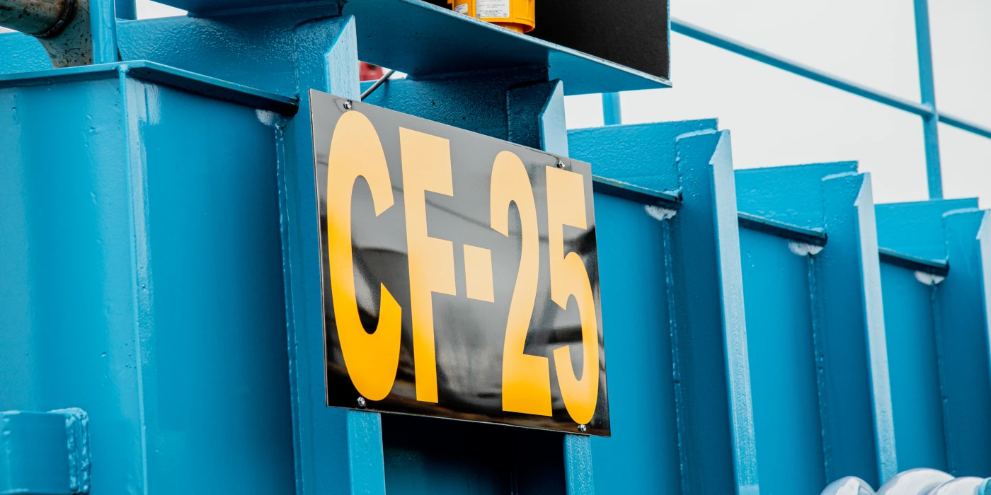 Large yellow letters CF-25 on a black sign attached to a blue industrial metal structure.
